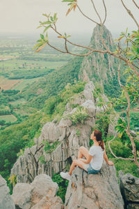 Rear view of woman sitting on rock