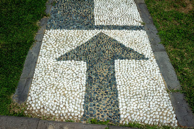 High angle view of arrow sign on footpath