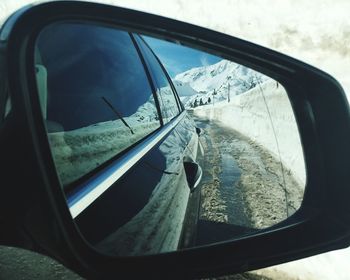 Side-view mirror of car with reflection during winter