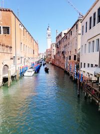 Boats in canal amidst buildings in city