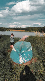 Woman standing by lake against sky