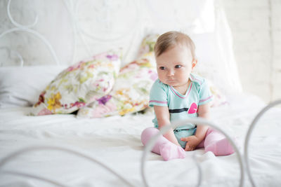 Cute baby girl lying on bed at home