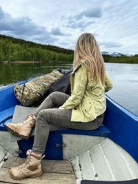 Woman sitting on boat in lake against sky