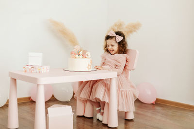 Happy little girl with a birthday cake at the table.