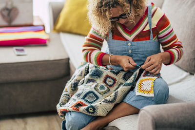 Midsection of woman knitting while sitting at home