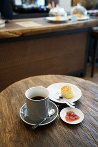 Close up hot black coffee with scone and fresh jam