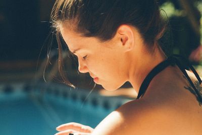 Side view of young woman in bikini sitting at poolside