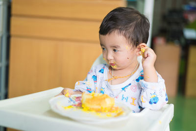 Cute boy sitting with dessert at home