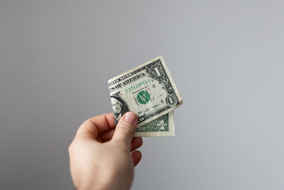 Cropped hand holding paper currency against white background