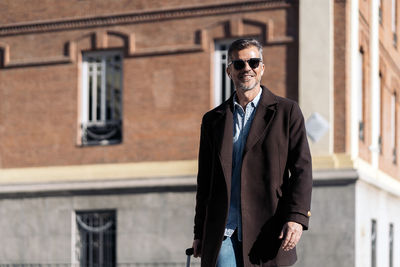 Portrait of man standing against building