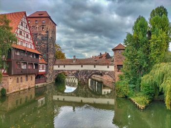 Arch bridge over river amidst buildings against sky