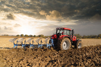 Tractor on field against sky during sunset