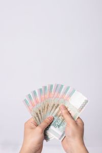 Low section of person holding paper against white background