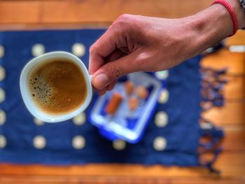 Cropped hand holding coffee on table