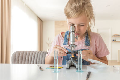 Girl looking through microscope at home