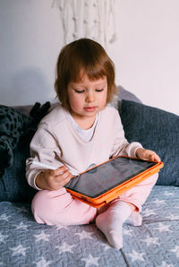 Portrait of cute girl sitting on sofa at home