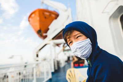 Boy wearing protective face mask while sitting in boat