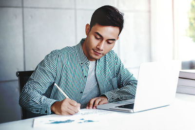 Young man using mobile phone while sitting on table