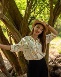 Portrait of smiling young woman standing by tree