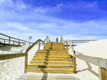 Low angle view of people standing on staircase against sky