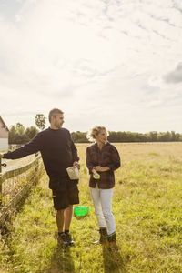 Rear view of friends standing on field against sky