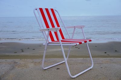 Deck chairs on beach against sky