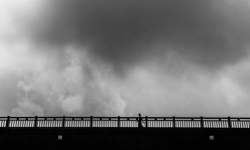 Silhouette smoke emitting from bridge against sky