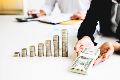 Midsection of business person with currency at desk in office