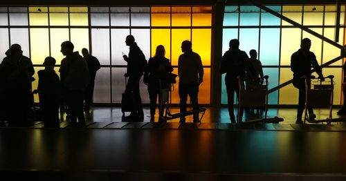 Silhouette people standing by window at airport