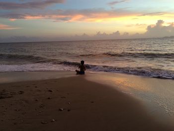 Silhouette woman standing on beach against sky during sunset