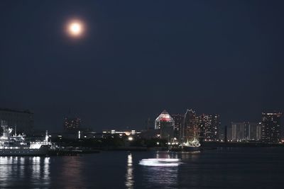 River against illuminated buildings in city at night