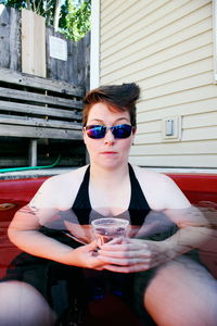 Woman holding disposable cup in bathtub outdoors