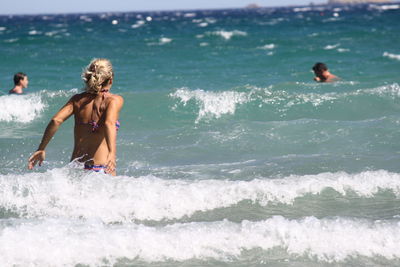 Full length of shirtless man surfing in sea