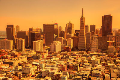 Aerial view of modern buildings in city against sky during sunset