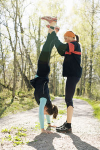 Woman helping sister doing handstand on road