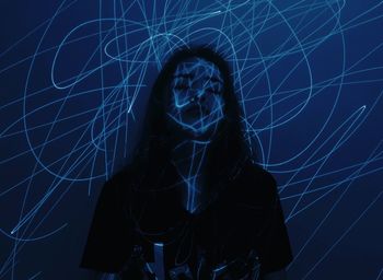Blue light on young woman standing against wall