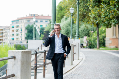 Full length of young man using mobile phone in city