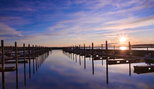 Reflection of pier in water at sunset