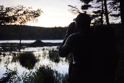 Rear view of silhouette couple by lake against sky