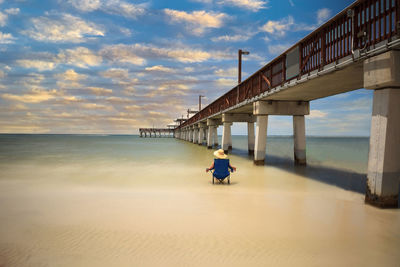 Man on pier over sea against sky