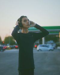 Side view of man with arms raised standing against sky