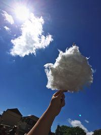 Cropped hand holding candy floss against sky