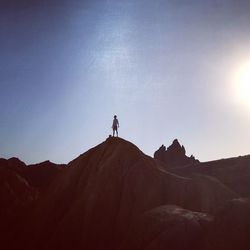 Man standing on rock by mountain against sky