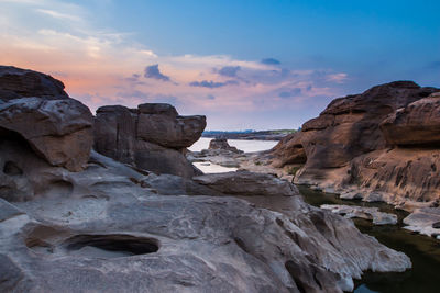 Rock formations in sea against sky during sunset