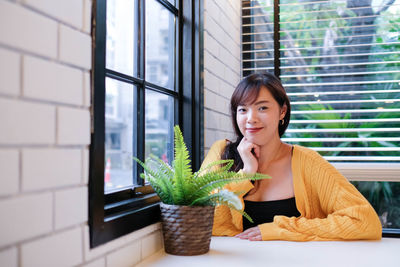 Portrait of woman with potted plants in window