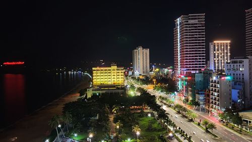 High angle view of illuminated street amidst buildings in city at night
