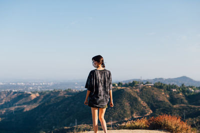 Full length rear view of woman standing on mountain