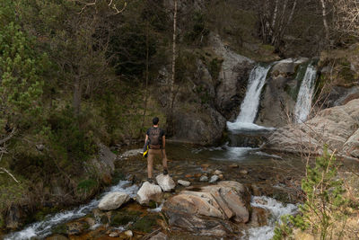 Man standing by waterfall in forest