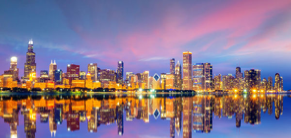 Reflection of illuminated buildings in city against sky