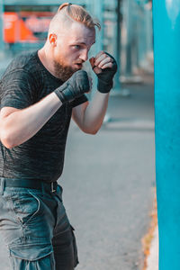 Young man looking away while standing outdoors